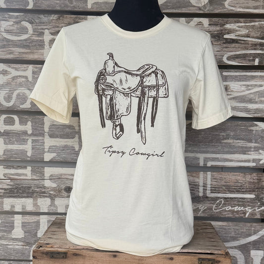 Tipsy Cowgirl The Saddle Tee in Natural featuring hand-drawn western saddle artwork and Tipsy Cowgirl signature