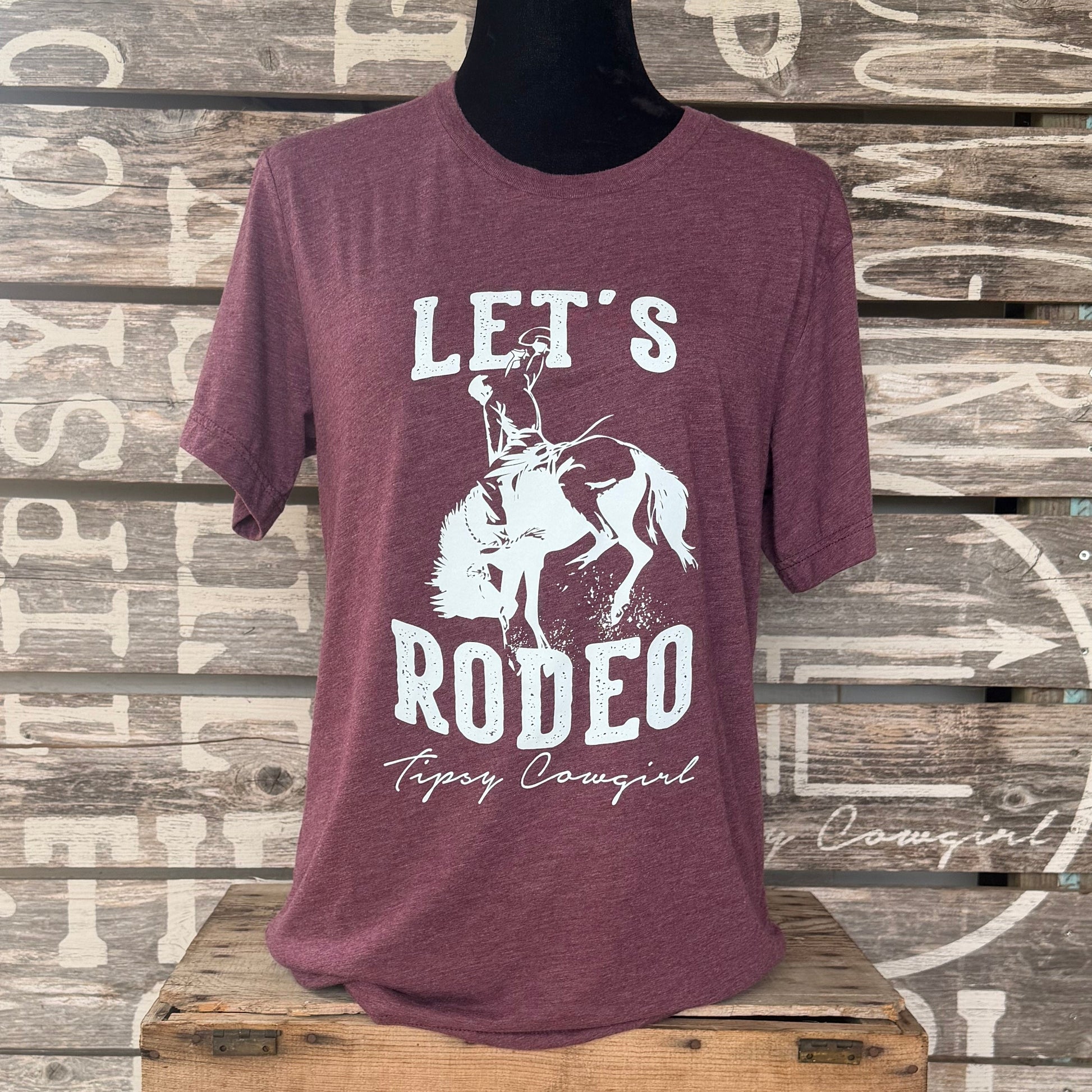 Tipsy Cowgirl Let's Rodeo tee in heather maroon featuring light blue bucking bronc western graphic and Tipsy Cowgirl signature